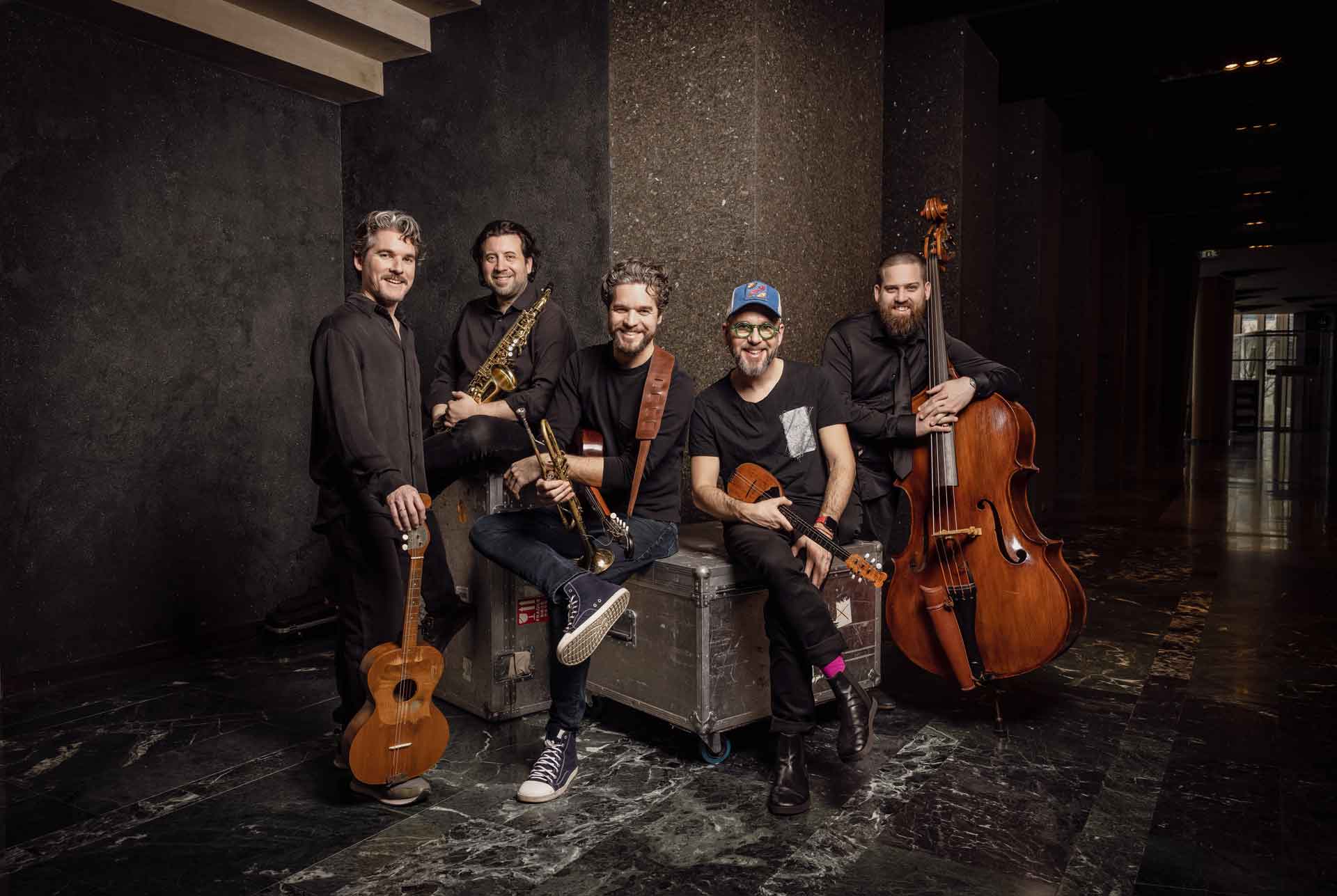 Söndörgő – fem glada musiker som håller i sina akustiska instrument
