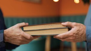 Två människors händer byter böcker med varandra