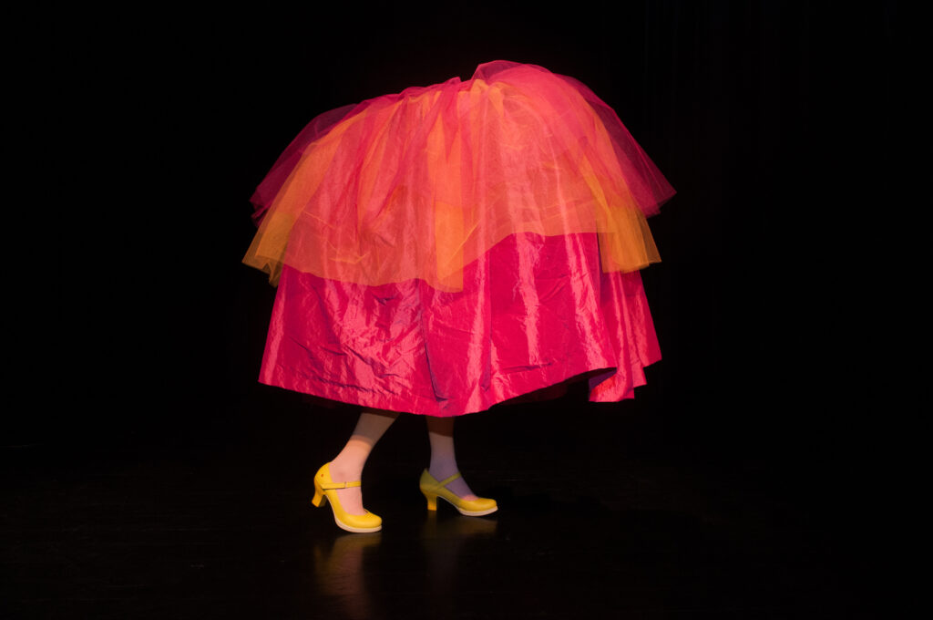 Barnföreställning Titta ut Rut. Ett par fötter med gula klackskor sticker ut under en stor tyllkjol.