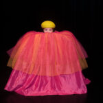 Barnföreställning Titta ut Rut. Skådespelare i gul basker som tittar upp ur stor tyllkjol.