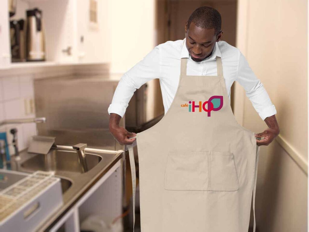 En man sätter på sig ett förkläde med texten "café iHoP" på. 