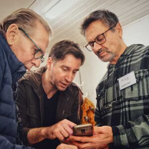 Tre män som studerar en gammal mobiltelefon