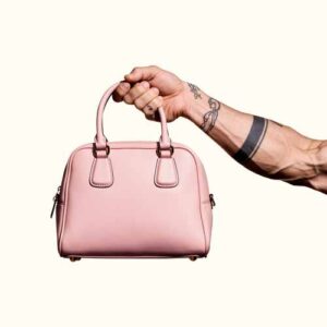 En muskulös arm håller i en rosa handväska