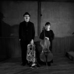 Svartvitt foto på två allvarliga musiker, en man med en tuba, en kvinna med en cello